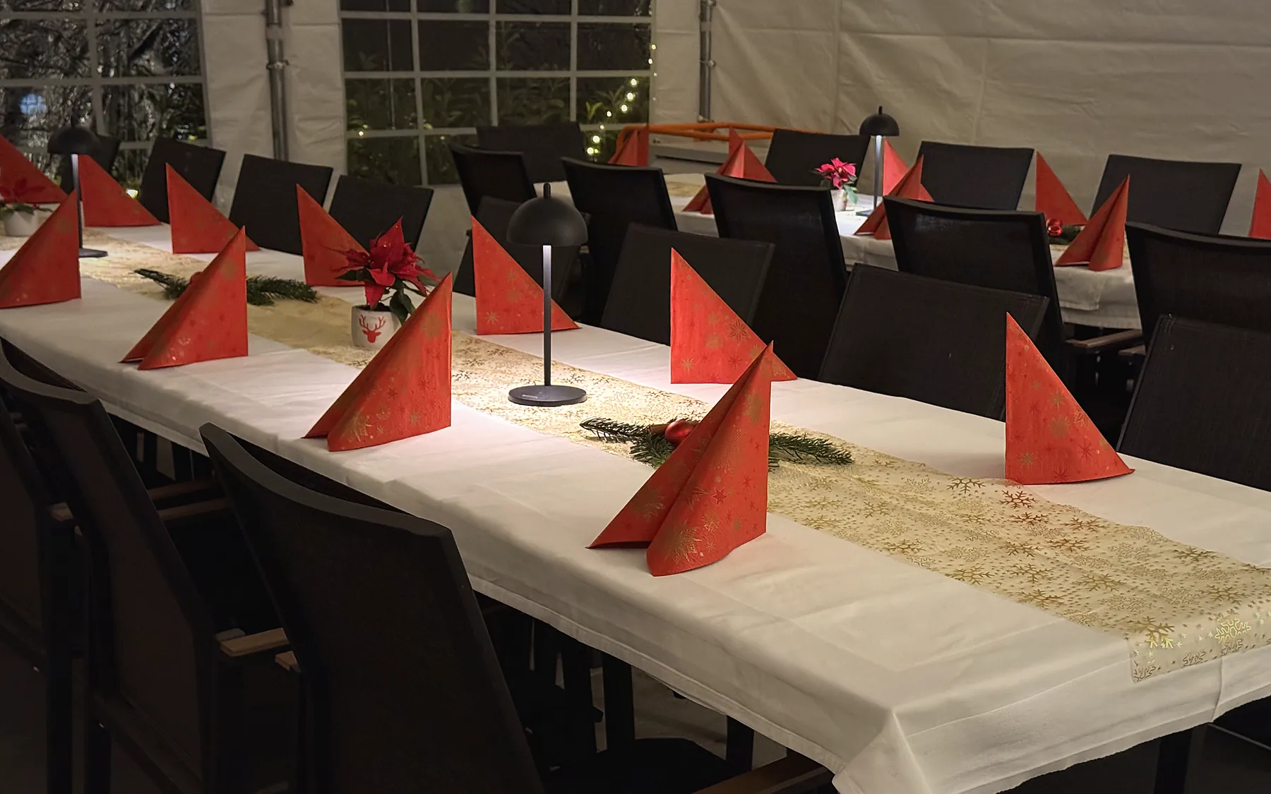 Lange, weiß gedeckte Festtafeln mit roten Servietten
