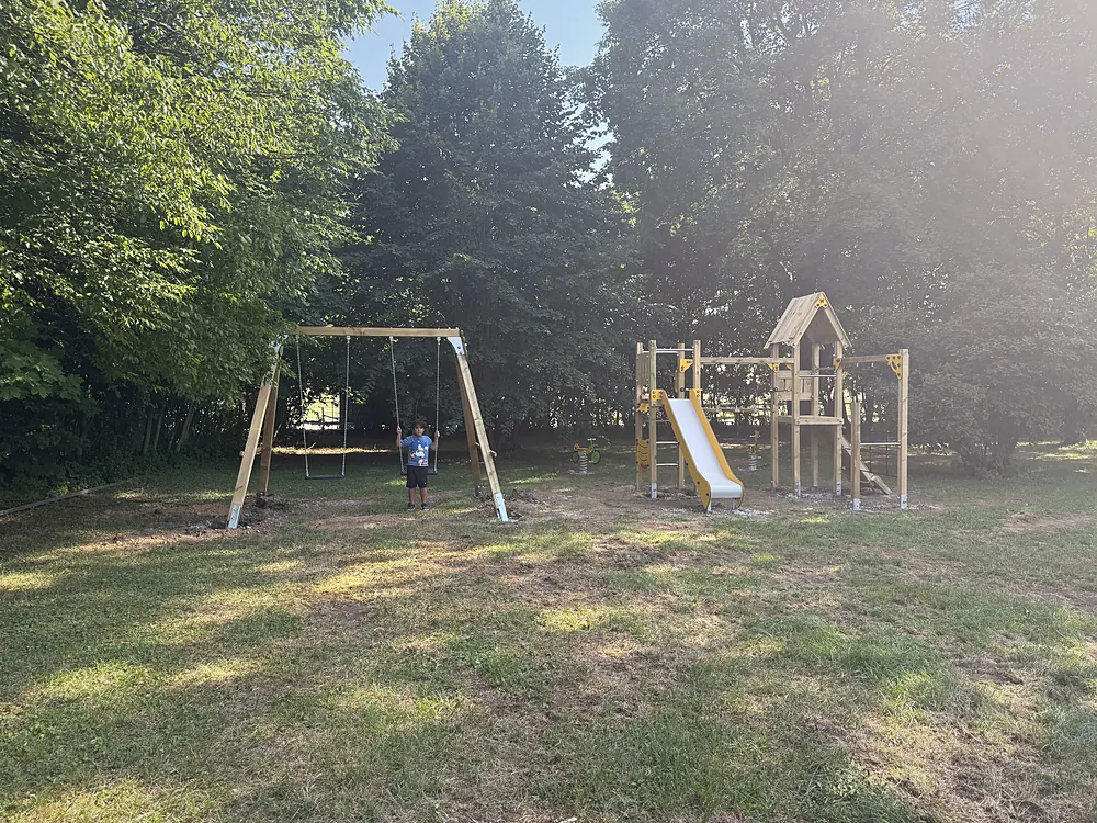 Spielplatz mit Schaukel und Klettergerüst im Grünen